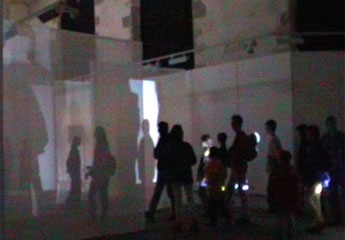 audience wandering around chapel - their shadows projected onto voile screens